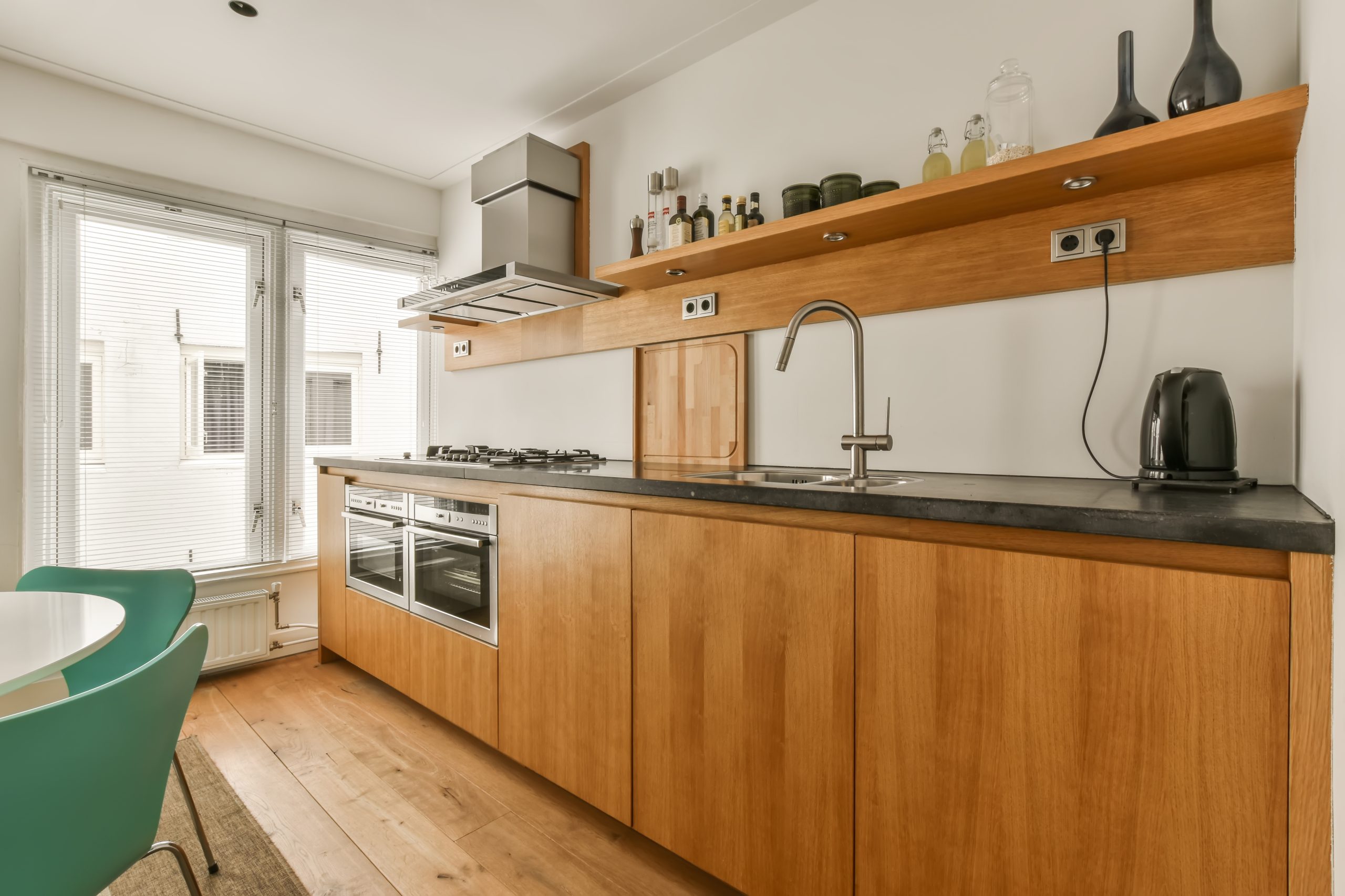 a kitchen and dining area in a house with wood cabinets, green chairs and white walls that have been painted