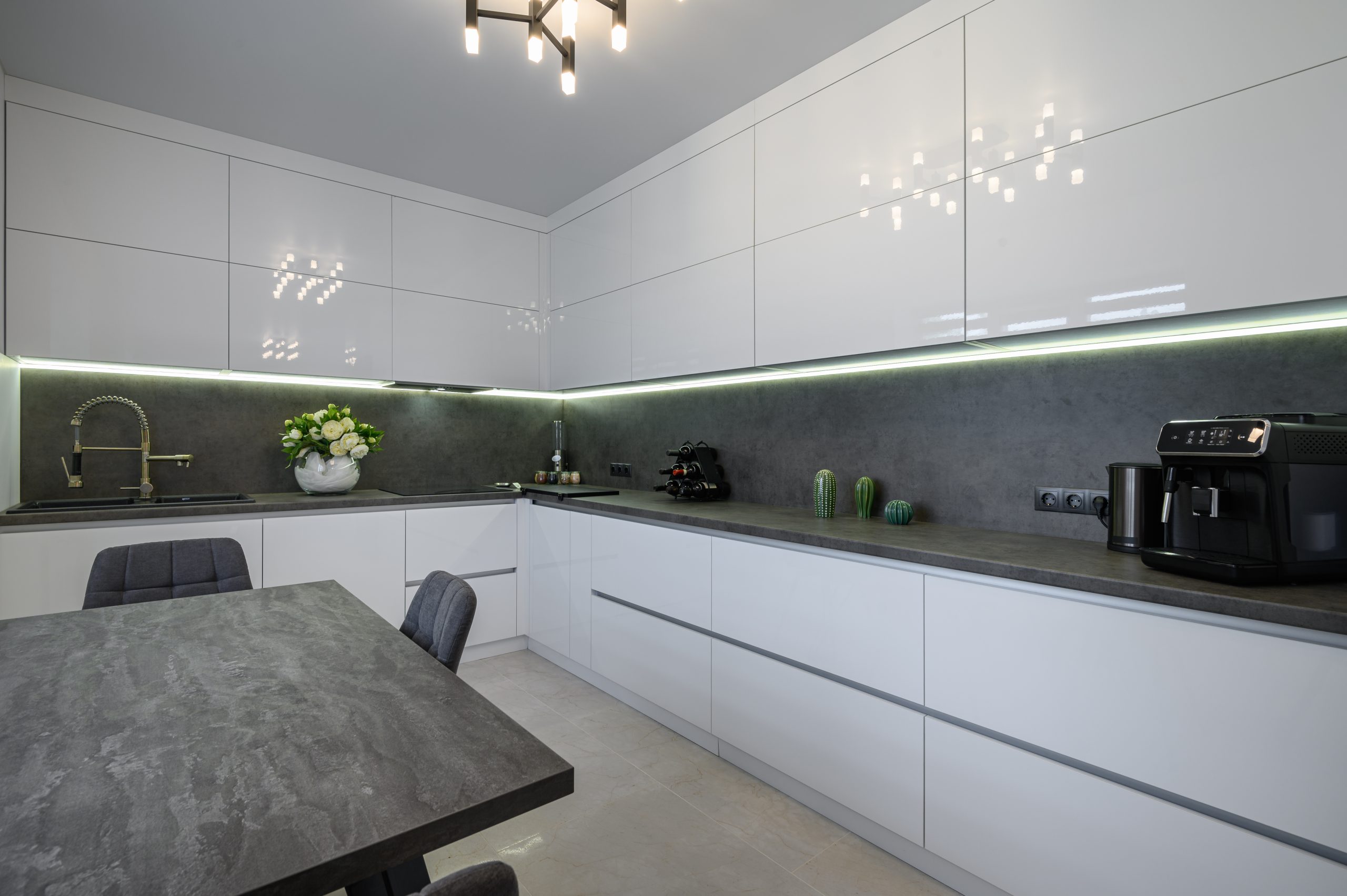 Luxurious modern trendy white and grey kitchen interior after renovation, with granite counter top